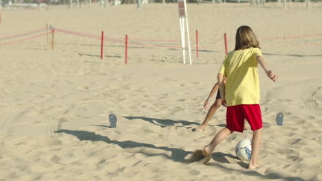 Slow-motion-of-boys-playing-soccer-together-on-public-beach